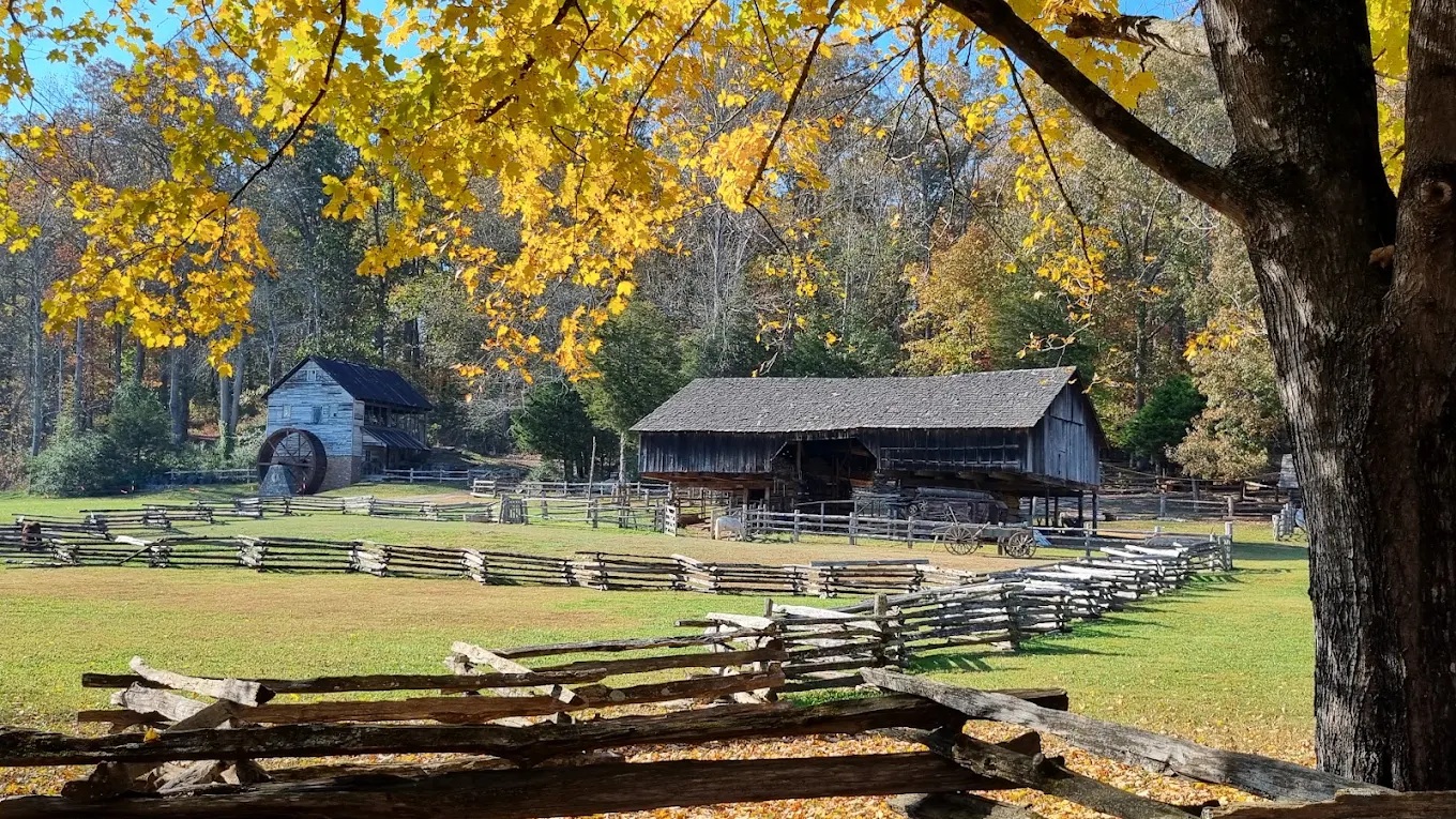 Historic mill and wooden buildings beneath golden autumn trees